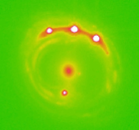 An optical image of the quasar RXJ1131-1231, magnified by a gravitational lens. The red spot in the center is the galaxy that is acting as a lens, while the four bright spots (three top, one bottom) are magnified images of the same quasar.