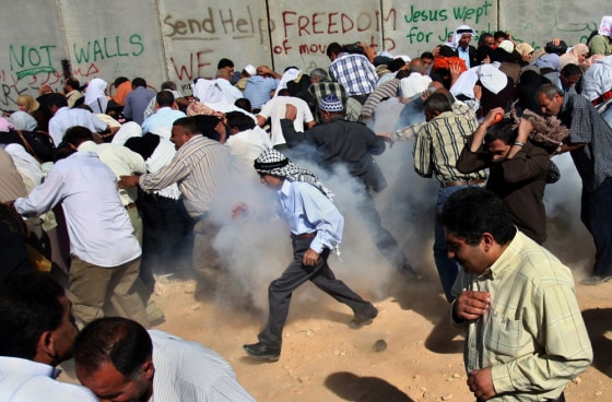 Palestinians run from the smoke after a concussion grenade was thrown by Israeli troops to disperse a crowd of worshippers at a checkpoint in the West Bank town of Bethlehem on Friday.