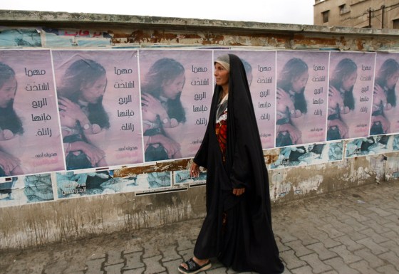A woman passes posters that read: "No matter how strong the storm, it will go away in the end" in Baghdad on Saturday.