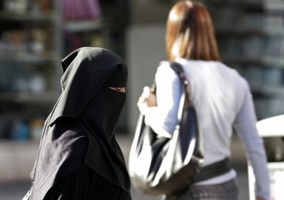 A Muslim woman wearing a veil walks along a road in the town in Blackburn, northern England