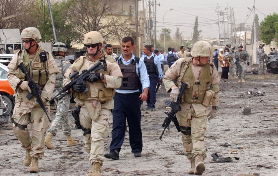 US soldiers and Iraqi police secure the scene of a suicide car bomb attack in Kirkuk