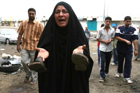 An Iraqi woman holds up the shoes of a relative who was killed in a car bomb blast that targeted a police patrol in central Baghdad on Monday. Three people died and 10 were wounded in the blast.