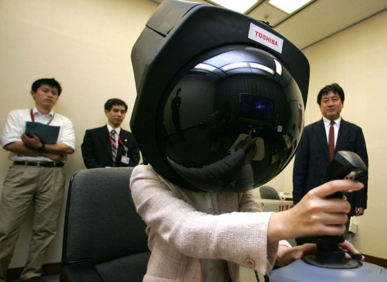 Toshiba Corp. employee Aira Hotta demonstrates prototype headgear that enables her to get a 360-degree view on a dome-shaped screen. Toshiba, which plans to market the gadget within 2 to 3 years, aiming at attracting people such as virtual reality gamers.