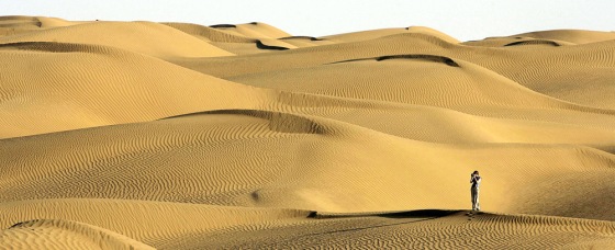 A visitor stands on sand dune in the Taklimakan Desert in northwest China's Xinjiang Uygur Autonomous Region, Wednesday, Oct. 11, 2006. The Taklimakan desert is one of the world's largest shifting sand deserts. (AP Photo/Eugene Hoshiko)