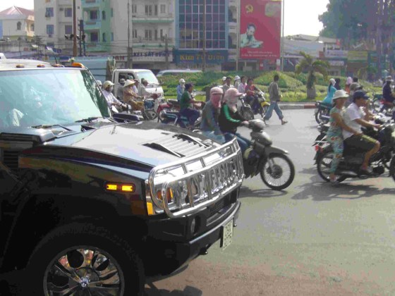 A Hummer sport utility vehicle competes with mopeds in traffic, in a sign of Vietnam's economic prosperity.