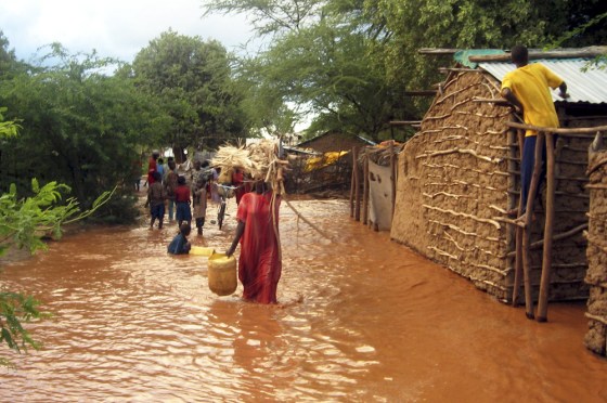 Displaced Kenyans carry their belongings though flood waters of Tana river in Garissa
