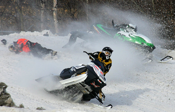 Two snowmobiles collide, knocking one rider off, as they race around the track during the Fur Rendezvous Sno-X races in Anchorage, Alaska, Feb. 26, 2005. The 17-day winter festival includes the World Championship Sled Dog races, dog weight pull, snow sculptures and other events to break up the long Alaska winter.