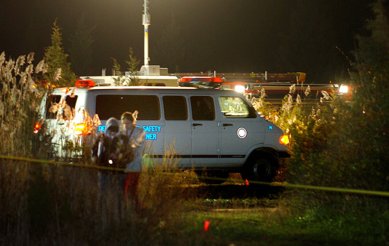 A police van moves into position to load a body at the site where four dead bodies were found in a ditch behind a motel, in Egg Harbor Township, N.J., on Monday.