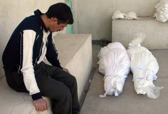 Iraqi man sits as he waits to claim the bodies of his father an mother outside morgue in Kerbala's cemetary