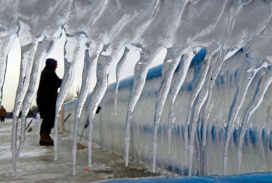 A fisherman is framed by icicles coating the railing of a pier at Lake Michigan in St. Joseph, Mich., on Tuesday. Storms packing ice and snow wreaked havoc across the Midwest last week, and thousands are still without power.