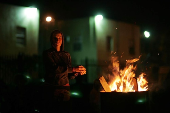 Lynne Purvis warms her hands over a fire as she takes a break from helping to build a shanty town in the Liberty City neighborhood, in Miami, Florida, on Oct. 24.