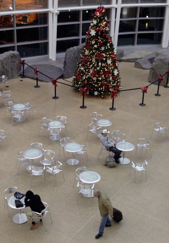 Passengers wait and walk past the largest Christmas tree at Sea-Tac Airport on Monday. The trees were taken down by Port of Seattle workers this past weekend after a local rabbi asked to have an 8-foot menorah displayed next to the tree in the international arriving hall. The trees were put back up Monday evening.
