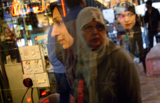 Zahra Khalid, 30, left, shops in the Al-Laith Compound shopping area in the Karrada district of Baghdad. The other women are shoppers who are reflected in the windows of the storefronts.