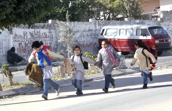 School girls run fleeing past an armed m