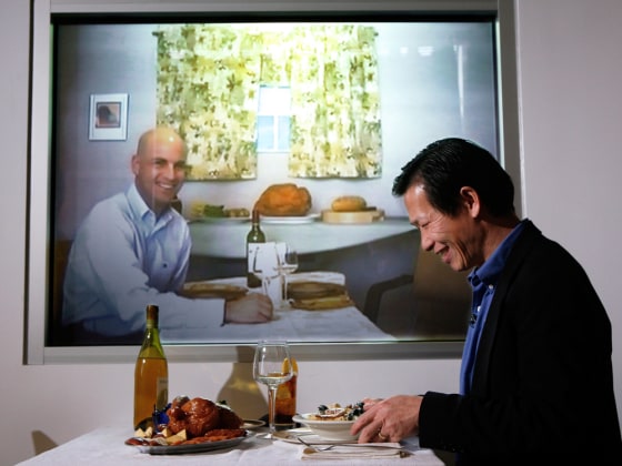 Accenture researchers Dadong Wan, right, and Adam Pilon, on screen, demonstrate a video-conferencing device that allows families to dine together from different locations.