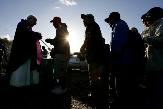 Worshipers receive communion from Monsignor Frank Fawcett during a service near McGonigle Canyon in Del Mar, Calif., on Dec. 17. 