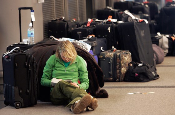 A woman reads a book at Denver International Airport on Tuesday near many pieces of luggage.