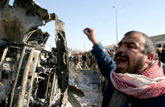 An Iraqi man cries out as he stands next to a destroyed car at the site of a explosion in Kufa, Iraq, on Dec. 30. Seventeen people died in the bomb blast.