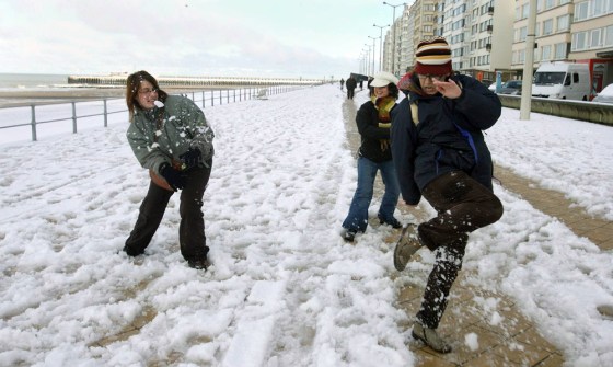 People enjoy the first snow on the beach