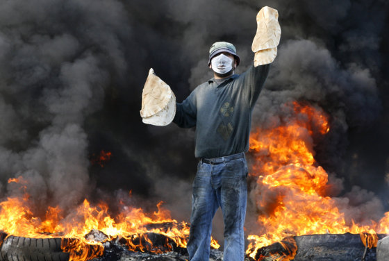A Lebanese protester holds up bread as he stands in front of burning tires in the southern city of Sidon on Jan. 23. Hezbollah-led opposition protesters seek to topple U.S.-backed Prime Minister Fuad Saniora.
