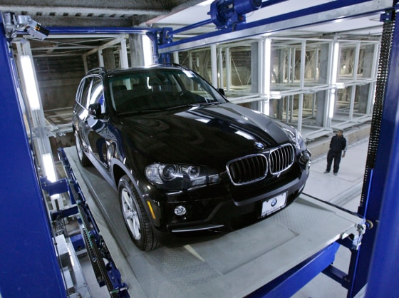 A construction worker watches as a robotic steel pallet lowers a vehicle into a completely automated parking garage in New York. The automated parking system is the first of its kind in the United States.