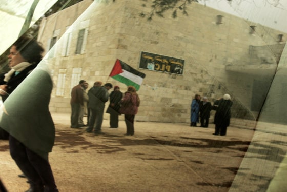 Palestinians, seen here reflected in a car window, wave their national flag during a protest calling for an end to Fatah-Hamas factional fighting, outside the Palestinian Legislative Council in the West Bank city of Ramallah on Tuesday. 