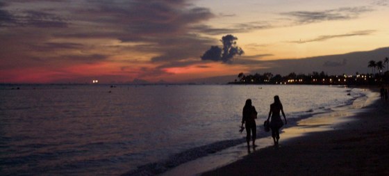 People walk along the beach as the sun sets on Waikiki.