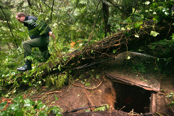 A police officer on Tuesday breaks through underbrush surrounding a tunnel where a suspected rapist had been living in Olympia, Wash.