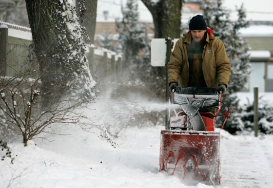 John Silvers of Columbus, Ohio, uses a snow blower to clear the sidewalk on Wednesday.