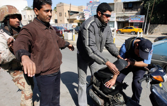 An Iraqi soldier and a policeman check residents at a checkpoint in Baghdad