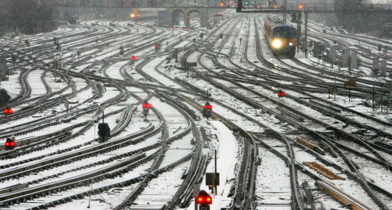 A mainline train bound for London's Waterloo station passes through snow covered railway lines in Clapham Junction station in south London