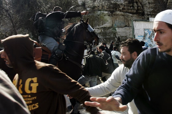 Palestinian men run as an Israeli police