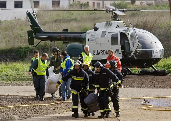 Civil Guard officers and firefighters carry plastic bags with the remains of the two persons found dead in the underground tunnel complex.