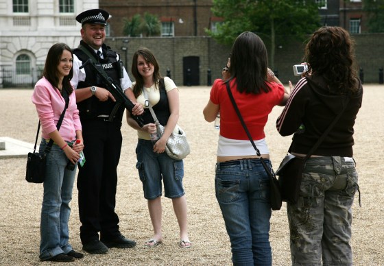 Unidentified tourists pose next to an armed British police officer as he stands guard at Horse Guards Parade in London.