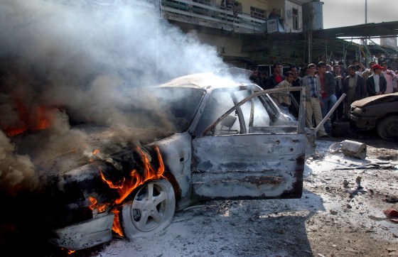 Iraqis gather at a car that caught fire after two bomb blasts in Kirkuk, 180 miles north of Baghdad, Iraq, on Saturday.