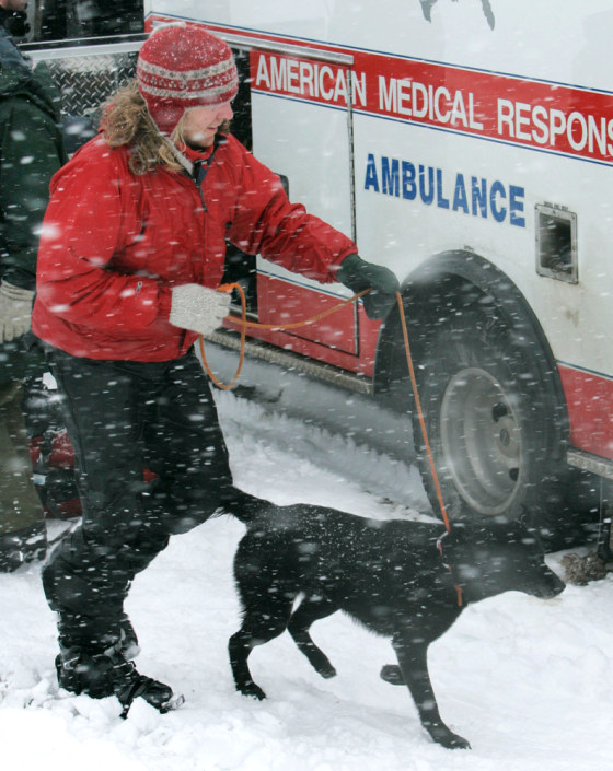 Matty Bryant, 34, of the Portland suburb of Milwaukie, one of the three climbers who were stranded on Mount Hood since Sunday runs to a waiting ambulance at White River snow park with a black Labrador named Velvet on Monday.