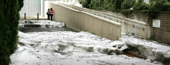 Students stand in a small street blocked with hail at the Australian National University in Canberra