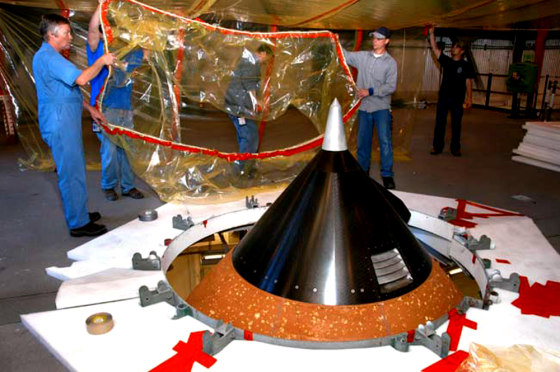 On an upper level of High Bay 1 in NASA's Vehicle Assembly Building, technicians move protective material toward the nose cone (foreground) of Atlantis' external tank. The nose cone will undergo repair for hail damage.