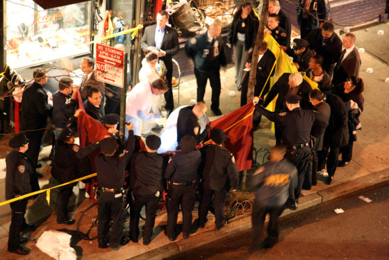 Policemen gather around the body of the gunman in New York's Greenwich Village on Wednesday night after he shot and killed a pizza parlor employee and two unarmed volunteer police officers who pursued him. The gunman was then shot to death by other police officers.