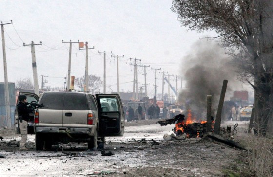A U.S. security guard stands near the still burning vehicle of a suicide attacker in Kabul, Afghanistan, on Monday. The car bomb exploded next to a U.S. Embassy convoy, pushing an embassy SUV across the road and setting it on fire, officials said.