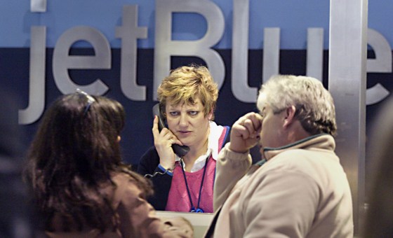 A JetBlue employee, center, helps passengers at the ticket counter during a storm at Boston's Logan Airport earlier this month.