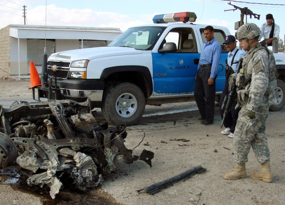 US soldier and Iraqi police inspect wreckage of a vehicle used in a car bomb attack in Ramadi