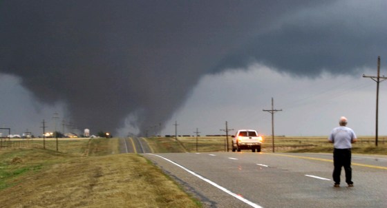 A man watches as a tornado crosses the highway east of the Northern Natural Gas Plant in Beaver County, Okla., on Wednesday.