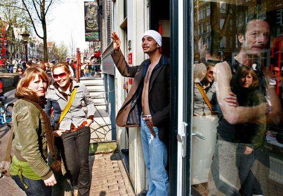 Passers-by walk past a prostitute's window during the open day in Amsterdam's red light district