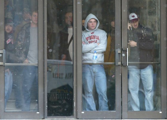 Virginia Tech students watch from a campus doorway as police move into the area where a shooting took place Monday.