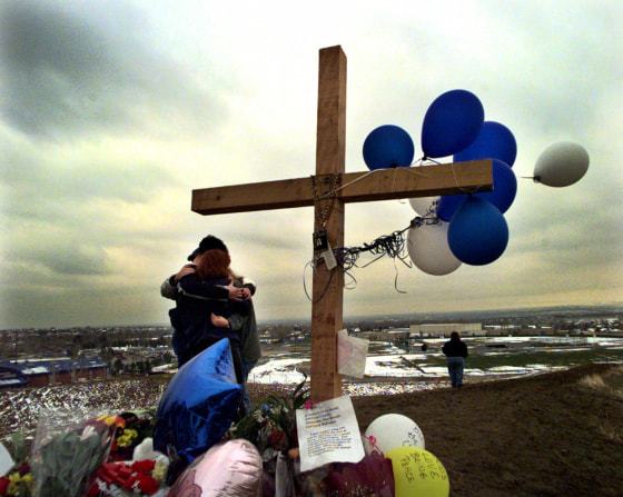 Unidentified students embrace each other at a makeshift memorial for their slain classmates at Columbine High School, on a hilltop overlooking the school in Littleton, Colo., in this April 24, 1999, file photo.
