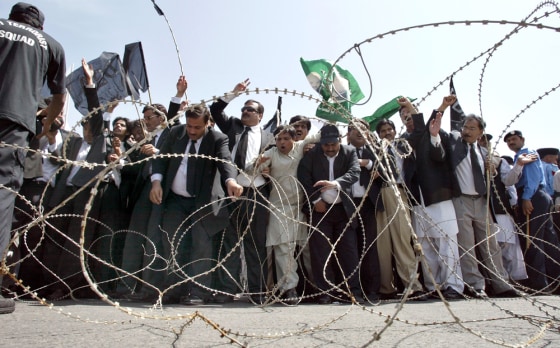 Pakistani lawyers and supporters of opposition parties chant slogans behind barbed wires during an anti-government rally near Supreme Court in Islamabad, Pakistan, on Tuesday. Rival rallies were held in the capital during a hearing on a top judge's suspension.