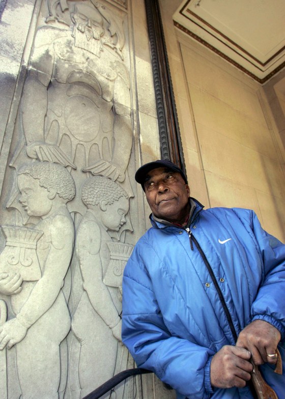 Local historian Eric Lynch stands next to a stone carving outside the Martins Bank Building in Liverpool, England. Liverpool's rise is summed up in the carving on a bank facade: two black children supporting Liverpool as Neptune, fellow historian Ray Costello says.