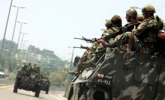 Lebanese soldiers ride on top of an armoured vehicle