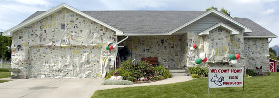 A sign welcoming home Mormon missionary Elder Brian Wigington stands in front of his newspaper-covered home in Providence, Utah, on Thursday.